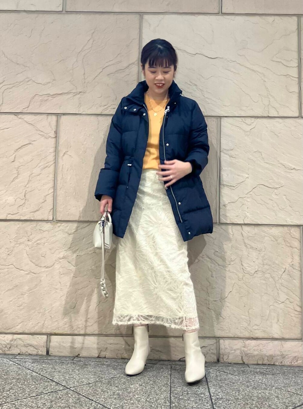 ベージュ系のブーツ、ブルー系のダウンジャケット/コート、オレンジ系のニット/セーターを着用したレディースの冬コーディネートの6枚目の写真