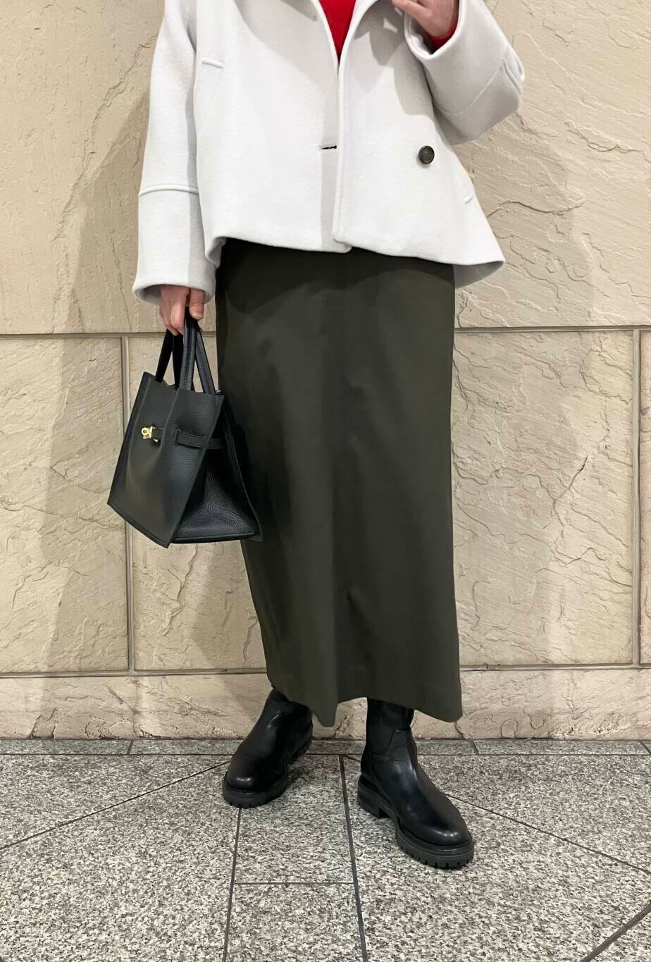 グリーン系のスカート、グレー系のピーコート、ブラック系のブーツを着用したレディースの冬コーディネートの5枚目の写真