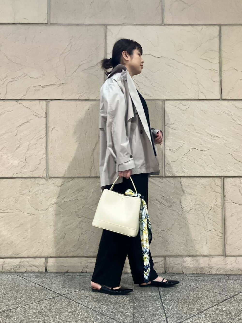 ブラック系のパンプス、ベージュ系のトレンチコート、ホワイト系のハンドバッグを着用したレディースの春コーディネートの3枚目の写真