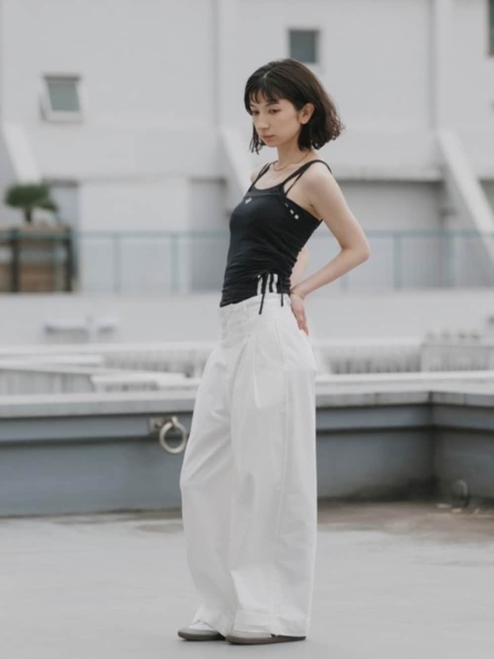 ブラック系のタンクトップ、ホワイト系のスラックスを着用したレディースの春コーディネートの2枚目の写真