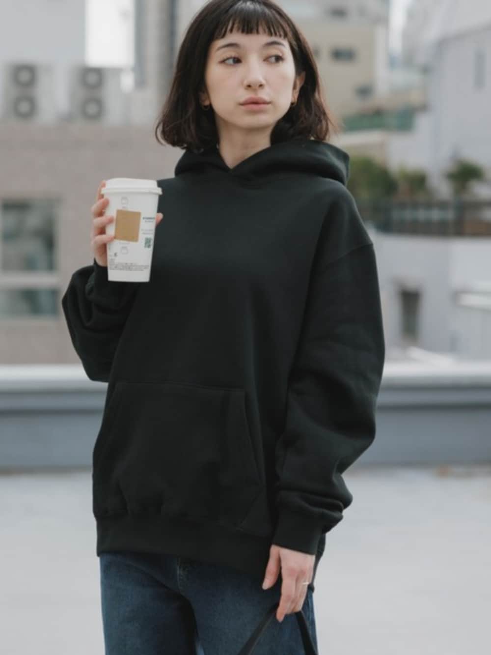 ブラック系のパーカー、ブラック系のデニムパンツを着用したレディースの春コーディネートの4枚目の写真