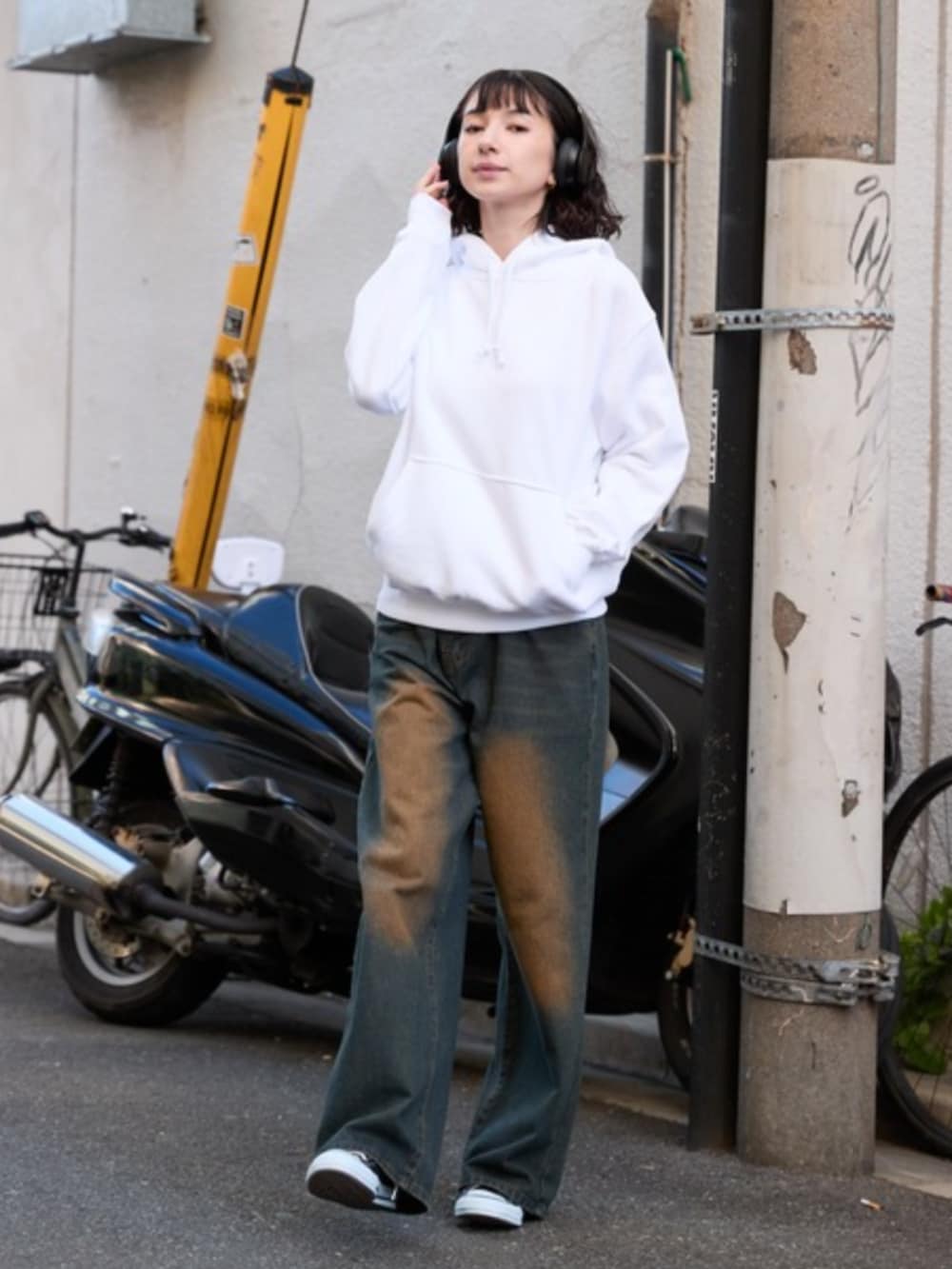 ホワイト系のパーカー、ブルー系のデニムパンツを着用したレディースの春コーディネートの2枚目の写真