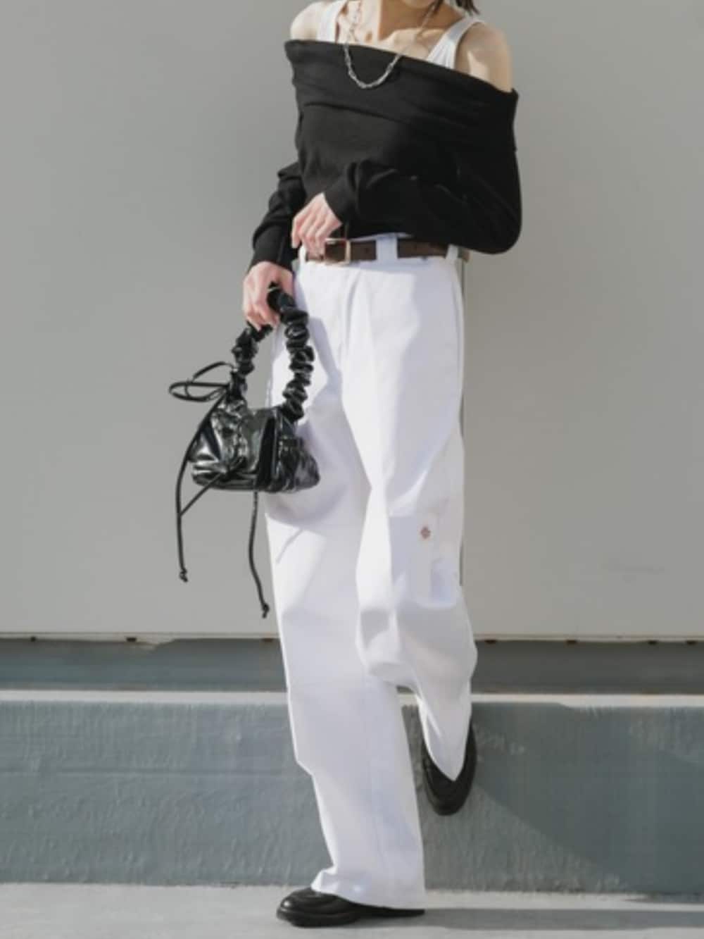 シルバー系のハンドバッグ、ホワイト系のチノパンツ、ブラック系のTシャツ/カットソーを着用したレディースの春コーディネートの2枚目の写真