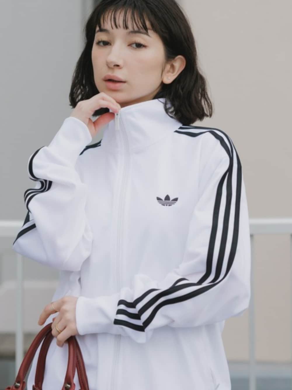 ホワイト系のジャージ、レッド系のショルダーバッグ、ブラック系のスニーカーを着用したレディースの春コーディネートの3枚目の写真