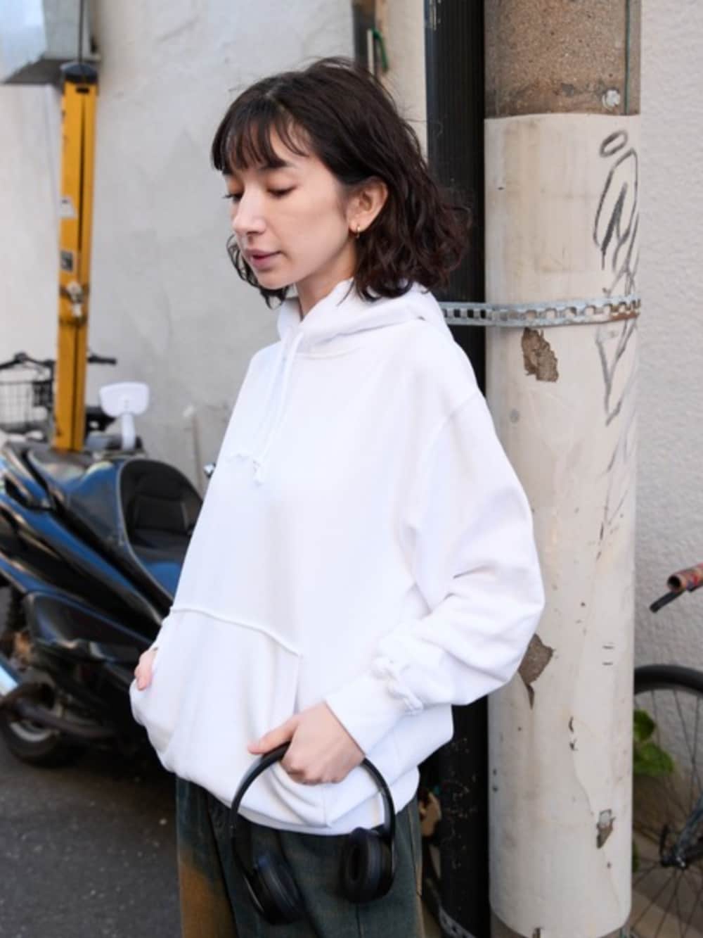 ホワイト系のパーカー、ブルー系のデニムパンツを着用したレディースの春コーディネートの3枚目の写真