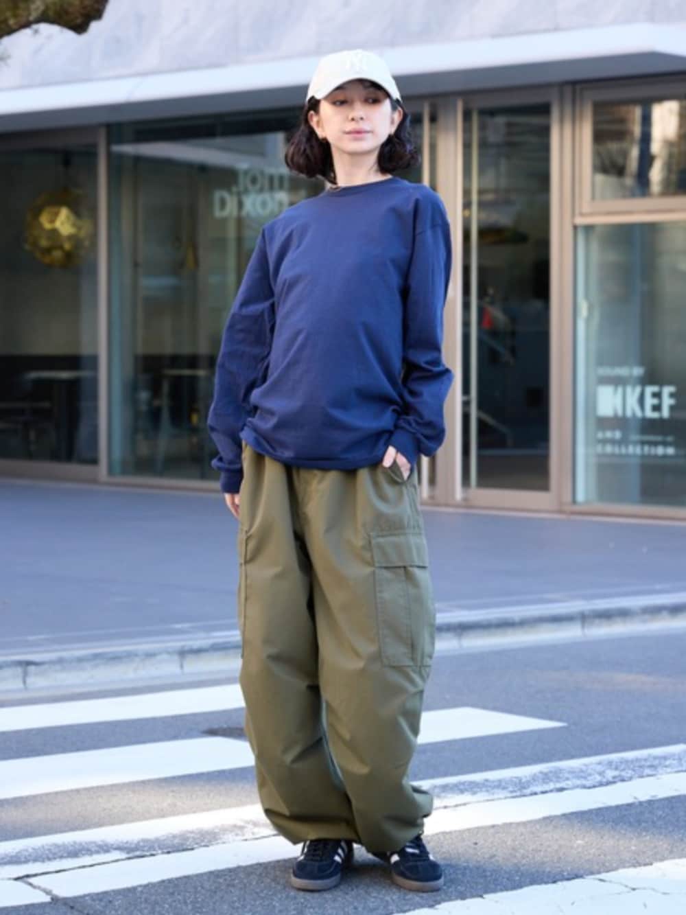 ブラック系のスニーカー、ブルー系のTシャツ/カットソー、グリーン系のカーゴパンツを着用したレディースの春コーディネートの2枚目の写真