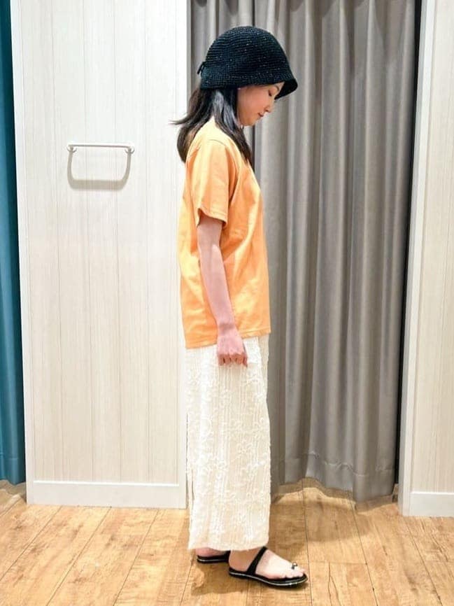 オレンジ系のTシャツ/カットソー、ホワイト系のスカート、ブラック系のサンダルを着用したレディースの夏コーディネートの2枚目の写真