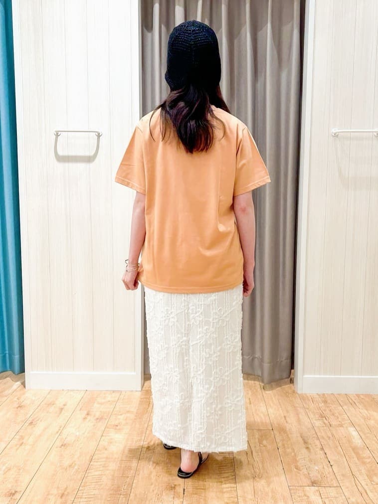 オレンジ系のTシャツ/カットソー、ホワイト系のスカート、ブラック系のサンダルを着用したレディースの夏コーディネートの3枚目の写真