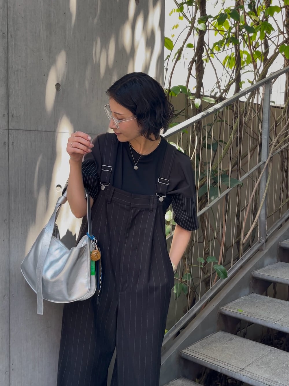 ブラック系のサロペット/オーバーオール、シルバー系のショルダーバッグ、ブラック系のTシャツ/カットソーを着用したレディースの春コーディネートの6枚目の写真