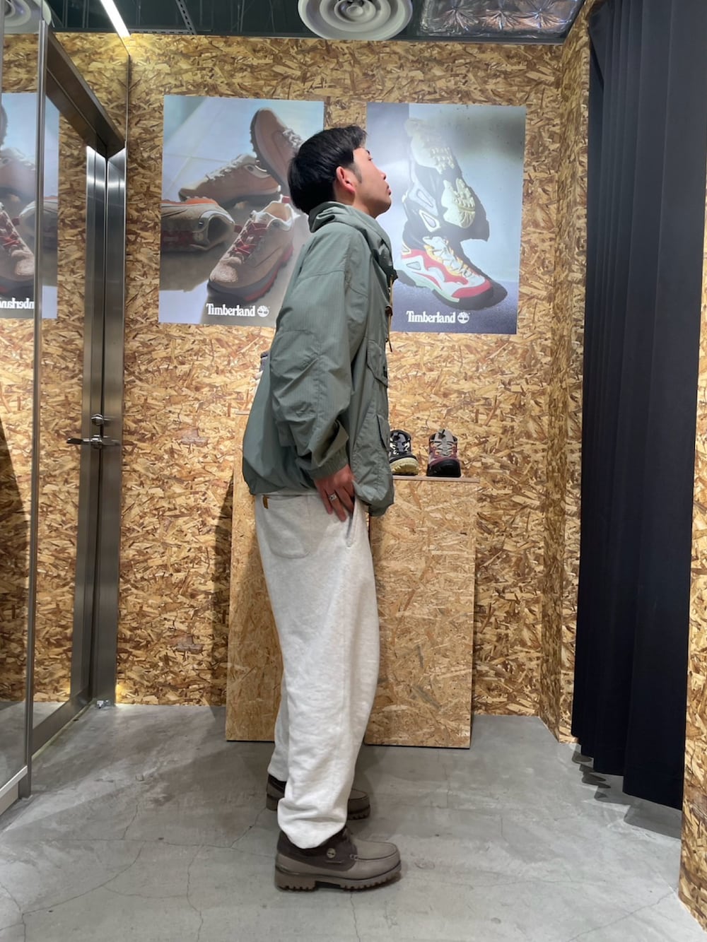 グリーン系のミリタリージャケット、グレー系のシューズ、ホワイト系のスウェットパンツを着用したメンズの春コーディネートの2枚目の写真