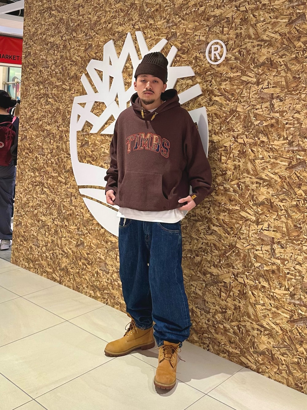 ブラウン系のパーカー、ベージュ系のブーツ、ブラウン系のニットキャップ/ビーニーを着用したメンズの秋コーディネートの2枚目の写真