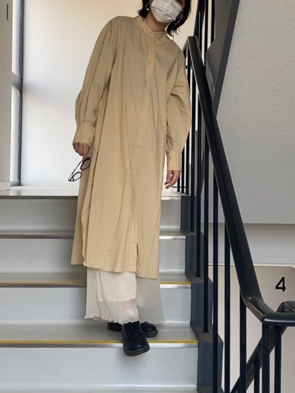 イエロー系のシャツワンピース、ホワイト系のネックレスを着用したレディースの春コーディネートの2枚目の写真