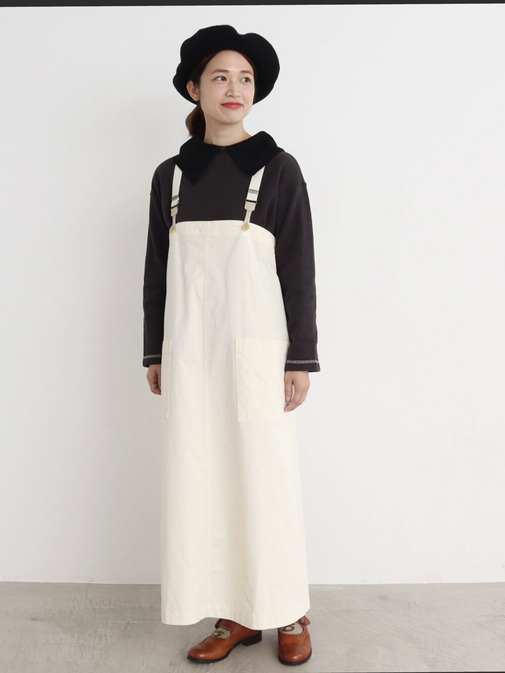 グリーン系のジャンパースカート、ベージュ系のパーカー、グレー系のニット/セーターを着用したレディースの冬コーディネートの4枚目の写真