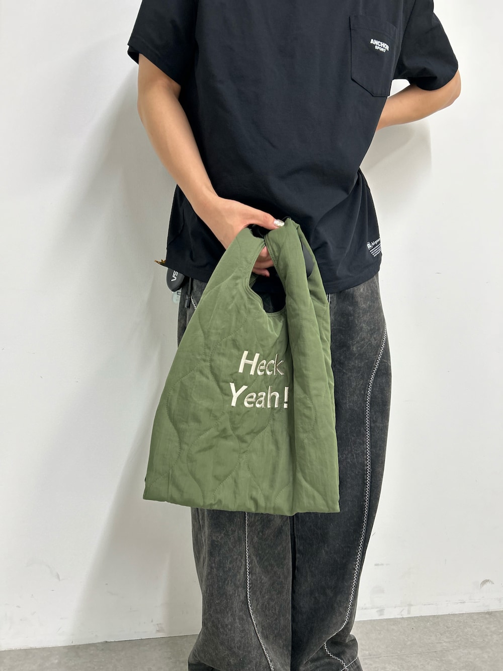 ブラック系のデニムパンツ、グリーン系のトートバッグ、ブラック系のスニーカーを着用したメンズの秋コーディネートの3枚目の写真