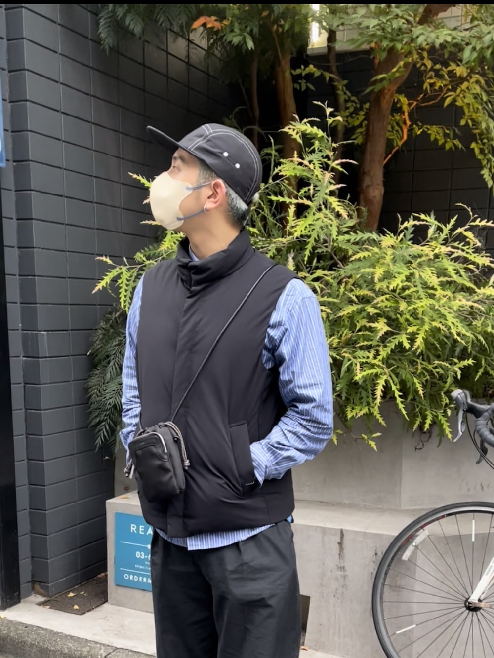 ブラック系のダウンベスト、ブルー系のシャツ/ブラウス、ブラック系のショルダーバッグを着用したメンズの秋コーディネートの2枚目の写真