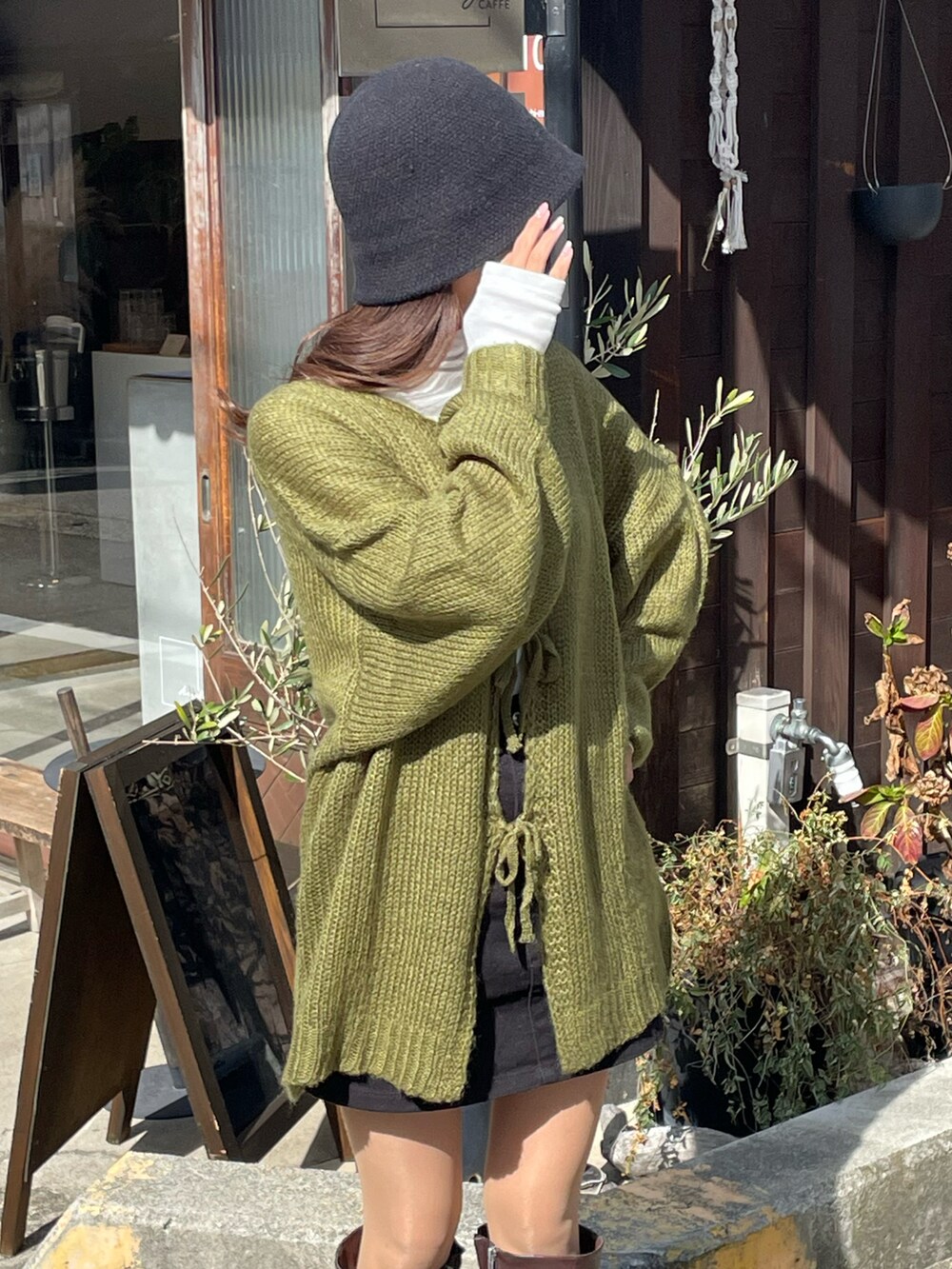 グリーン系のニット/セーター、ホワイト系のTシャツ/カットソー、ブラウン系のブーツを着用したレディースの秋コーディネートの2枚目の写真