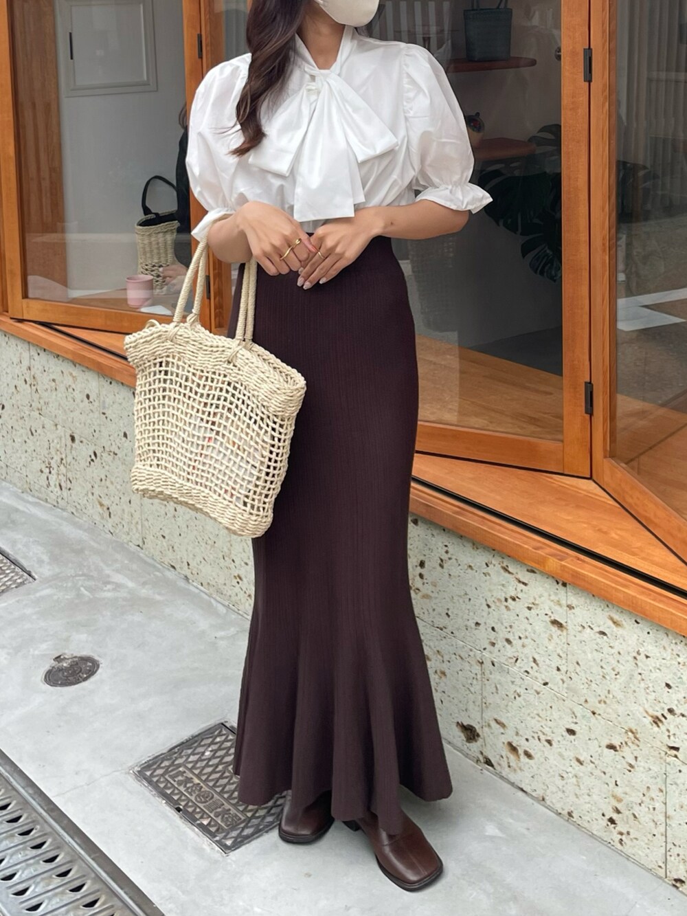 ホワイト系のシャツ/ブラウス、ブラウン系のスカート、ベージュ系のかごバッグを着用したレディースの春コーディネートの2枚目の写真