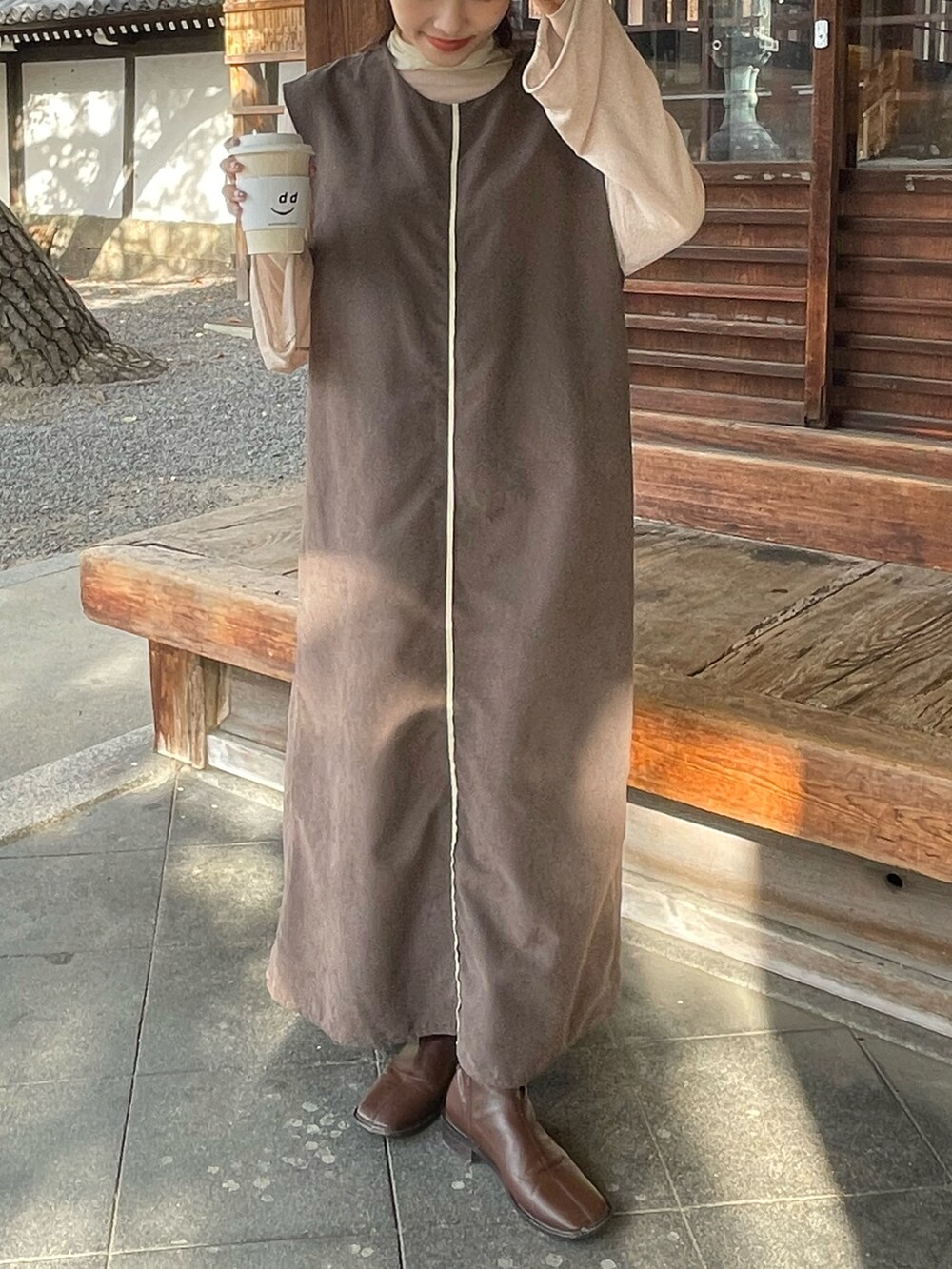 ブラウン系のワンピース、ベージュ系のニット/セーター、ブラウン系のブーツを着用したレディースの秋コーディネートの3枚目の写真