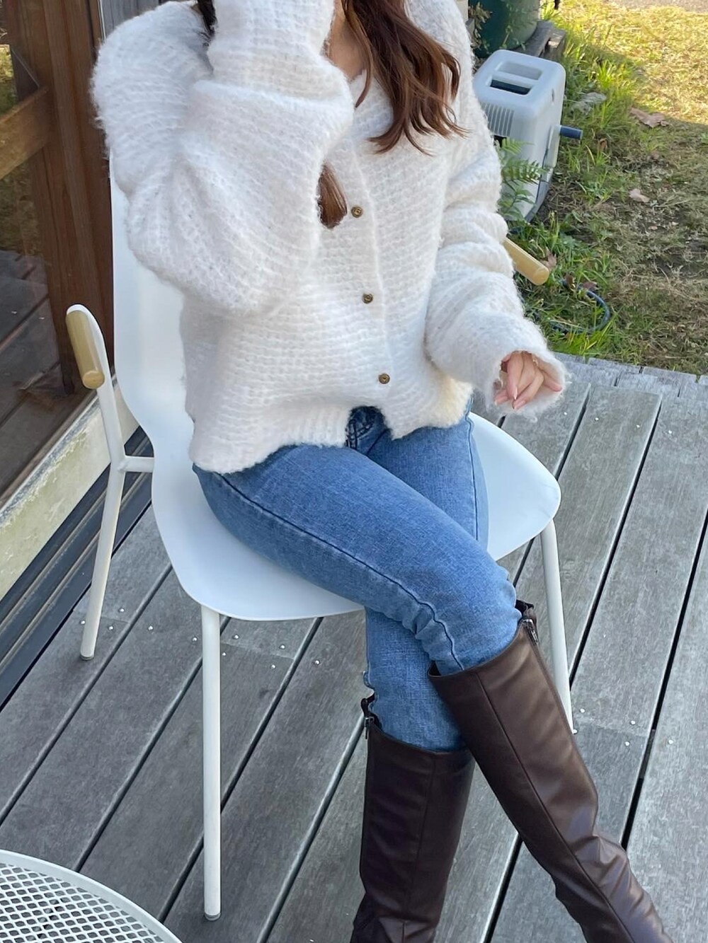 ホワイト系のカーディガン/ボレロ、ブルー系のデニムパンツ、ブラウン系のブーツを着用したレディースの冬コーディネートの2枚目の写真