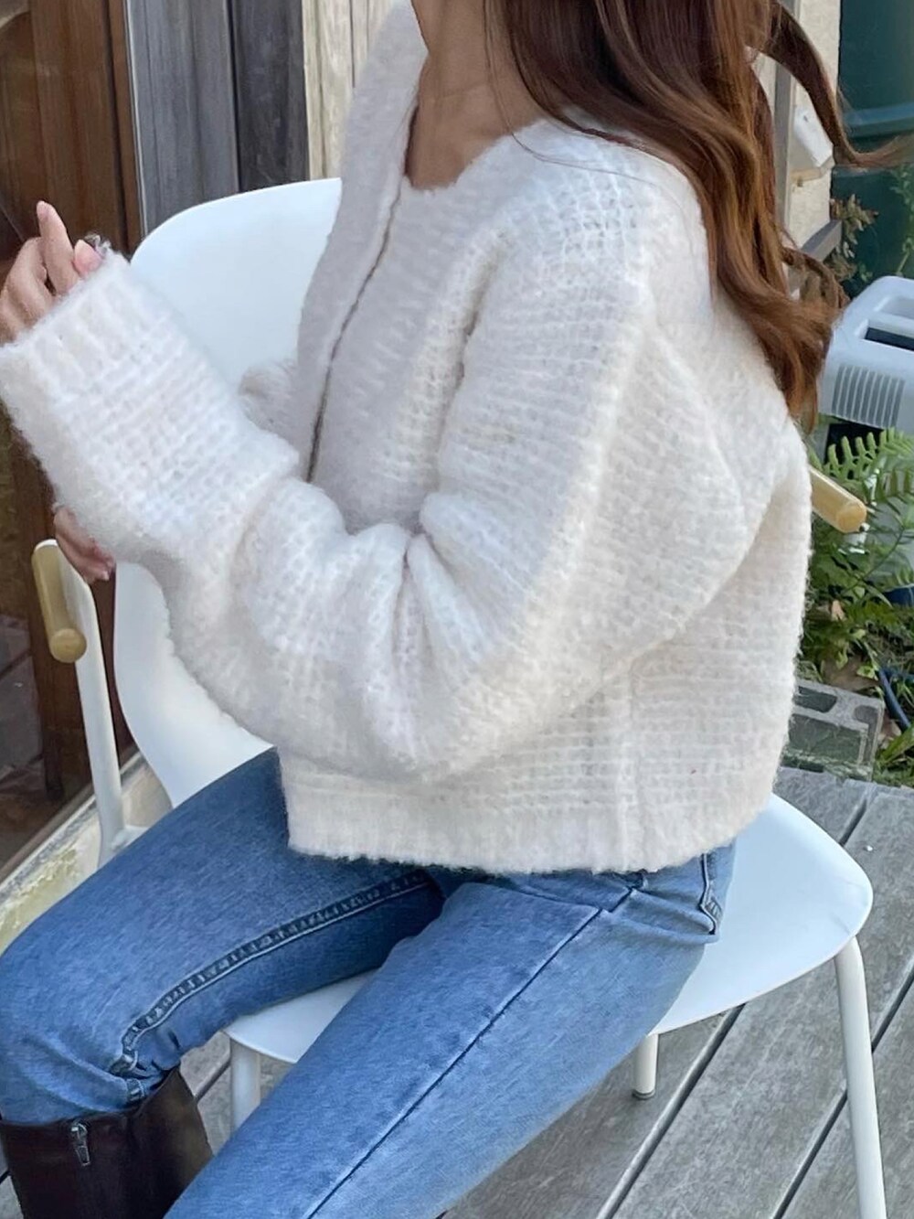 ホワイト系のカーディガン/ボレロ、ブルー系のデニムパンツ、ブラウン系のブーツを着用したレディースの冬コーディネートの3枚目の写真