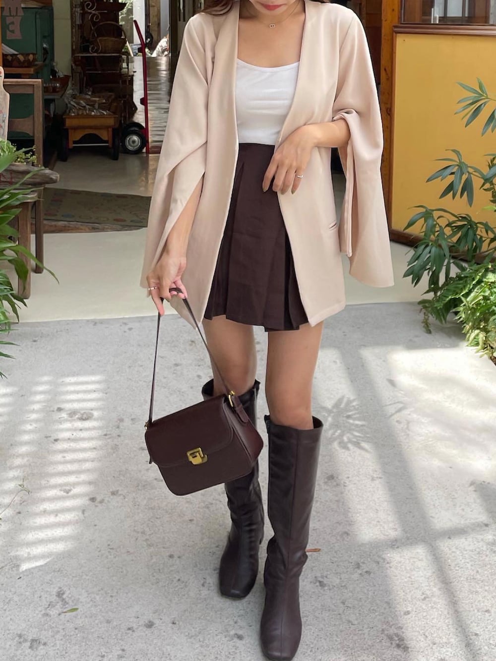 ブラウン系のスカート、ホワイト系のノーカラージャケット、ブラウン系のブーツを着用したレディースの秋コーディネートの2枚目の写真