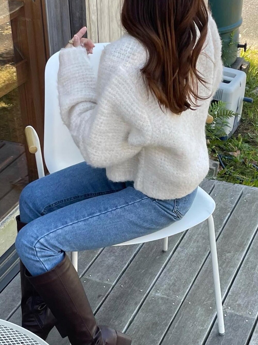 ホワイト系のカーディガン/ボレロ、ブルー系のデニムパンツ、ブラウン系のブーツを着用したレディースの冬コーディネートの4枚目の写真