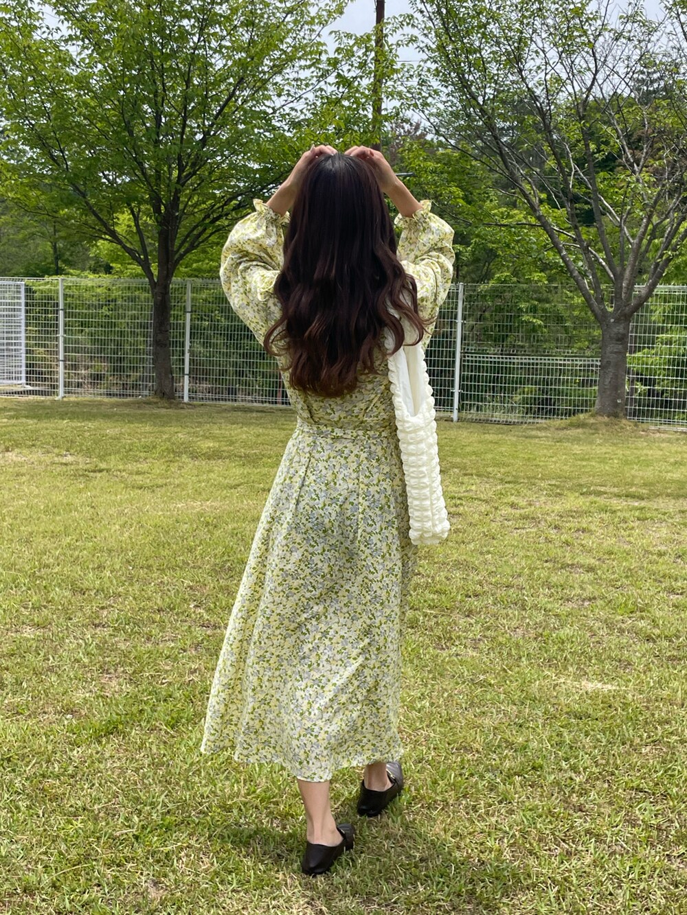 ホワイト系のトートバッグ、イエロー系のワンピース、ブラウン系のローファーを着用したレディースの夏コーディネートの3枚目の写真