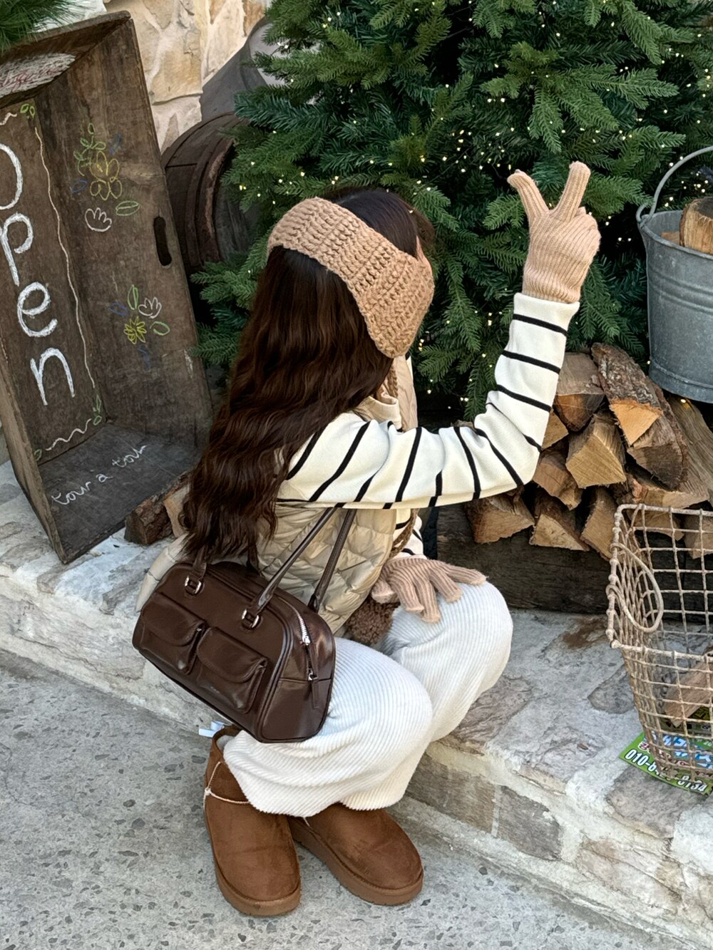 ブラウン系のバッグ、ブラウン系のブーツ、ホワイト系のニット/セーターを着用したレディースの冬コーディネートの3枚目の写真