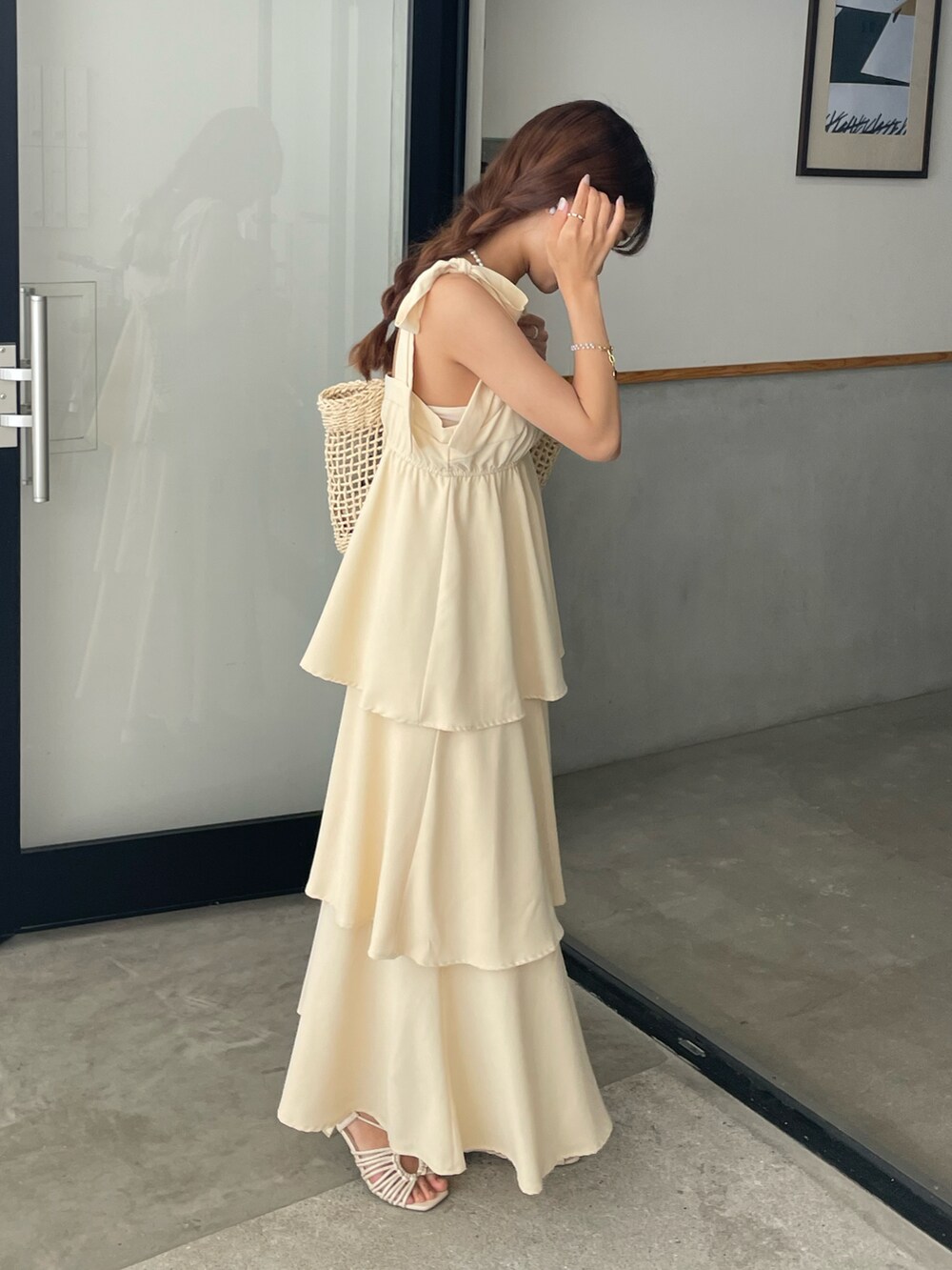 ホワイト系のサンダル、イエロー系のワンピース、ベージュ系のかごバッグを着用したレディースの夏コーディネートの2枚目の写真