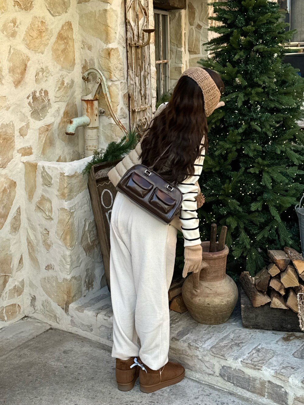 ブラウン系のバッグ、ブラウン系のブーツ、ホワイト系のニット/セーターを着用したレディースの冬コーディネートの2枚目の写真