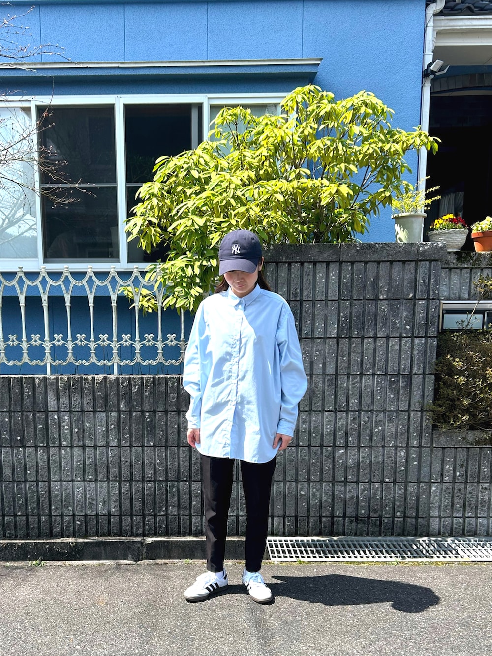 グレー系のスラックス、ブラック系のカーディガン/ボレロ、ホワイト系のスニーカーを着用したレディースの春コーディネートの2枚目の写真