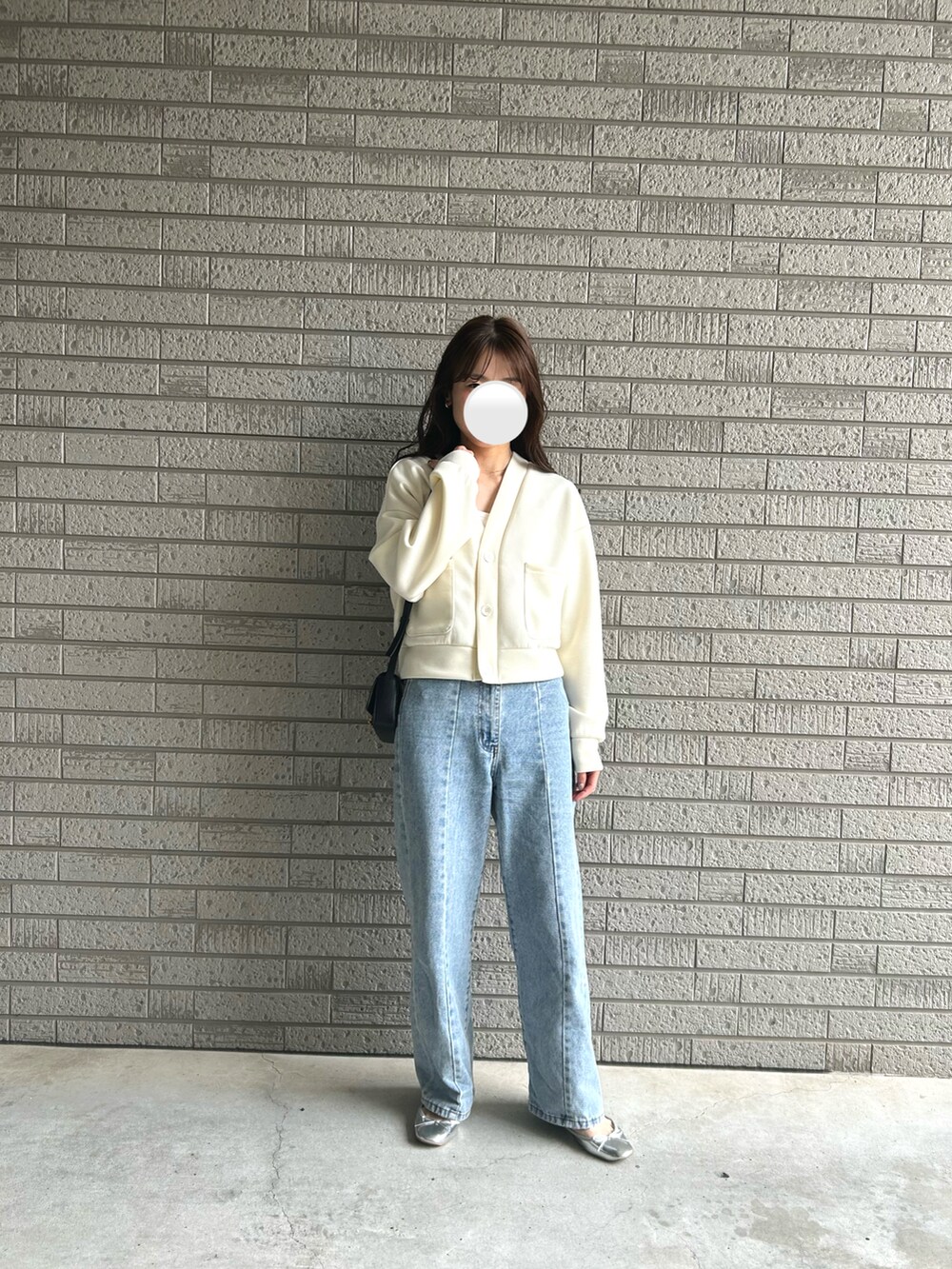 ブルー系のデニムパンツ、ホワイト系のカーディガン/ボレロ、ブラック系のバッグを着用したレディースの春コーディネートの2枚目の写真