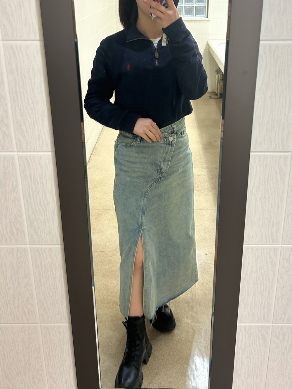 ブルー系のデニムスカート、ブラック系のトップス、ブラック系のブーツを着用したレディースの冬コーディネートの2枚目の写真