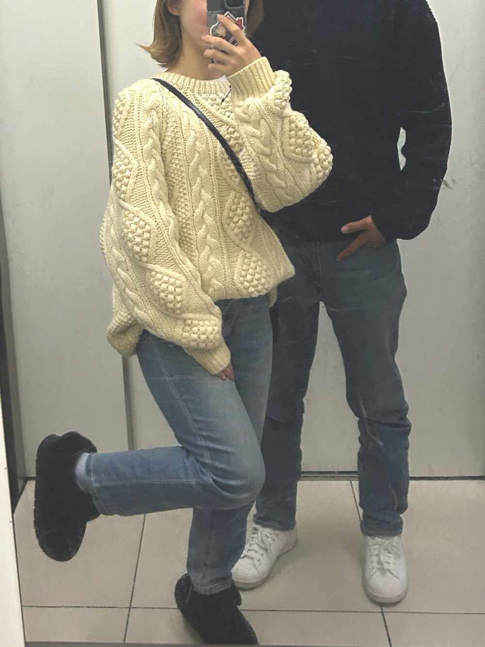 ブルー系のデニムパンツ、ブラック系のシューズ、ベージュ系のニット/セーターを着用したレディースの冬コーディネートの2枚目の写真