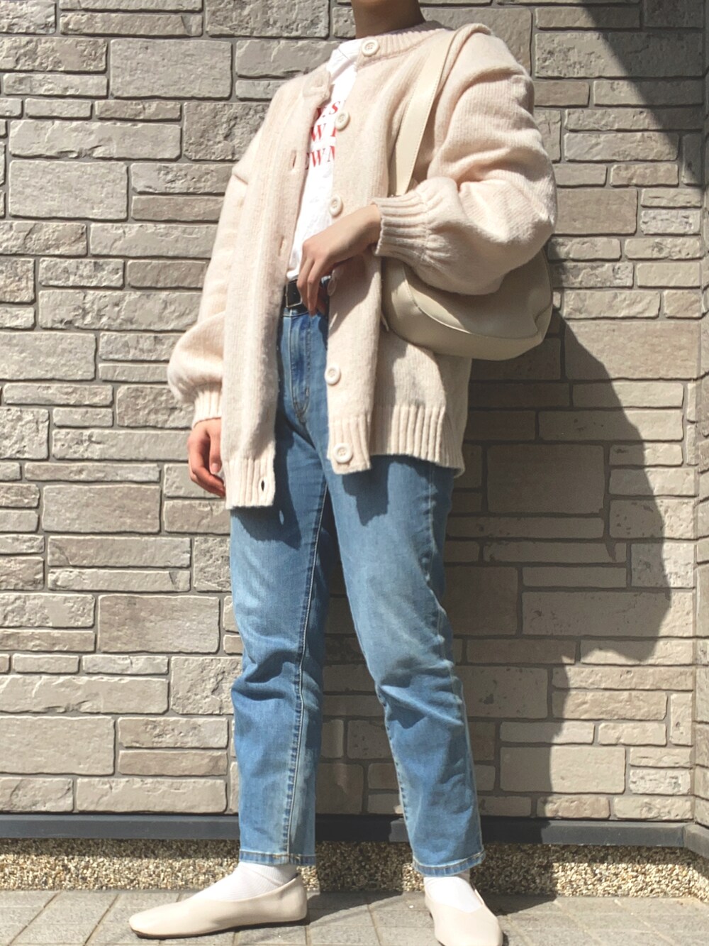 ブルー系のデニムパンツ、ホワイト系のトップス、ベージュ系のカーディガン/ボレロを着用したレディースの春コーディネートの2枚目の写真