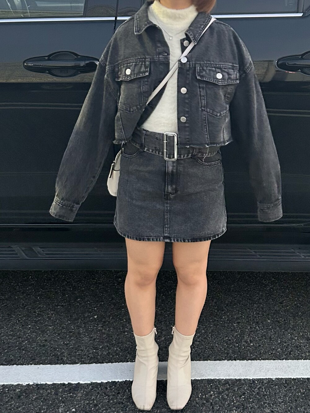 ブラック系のデニムスカート、ブラック系のデニムジャケット、ベージュ系のニット/セーターを着用したレディースの冬コーディネートの2枚目の写真