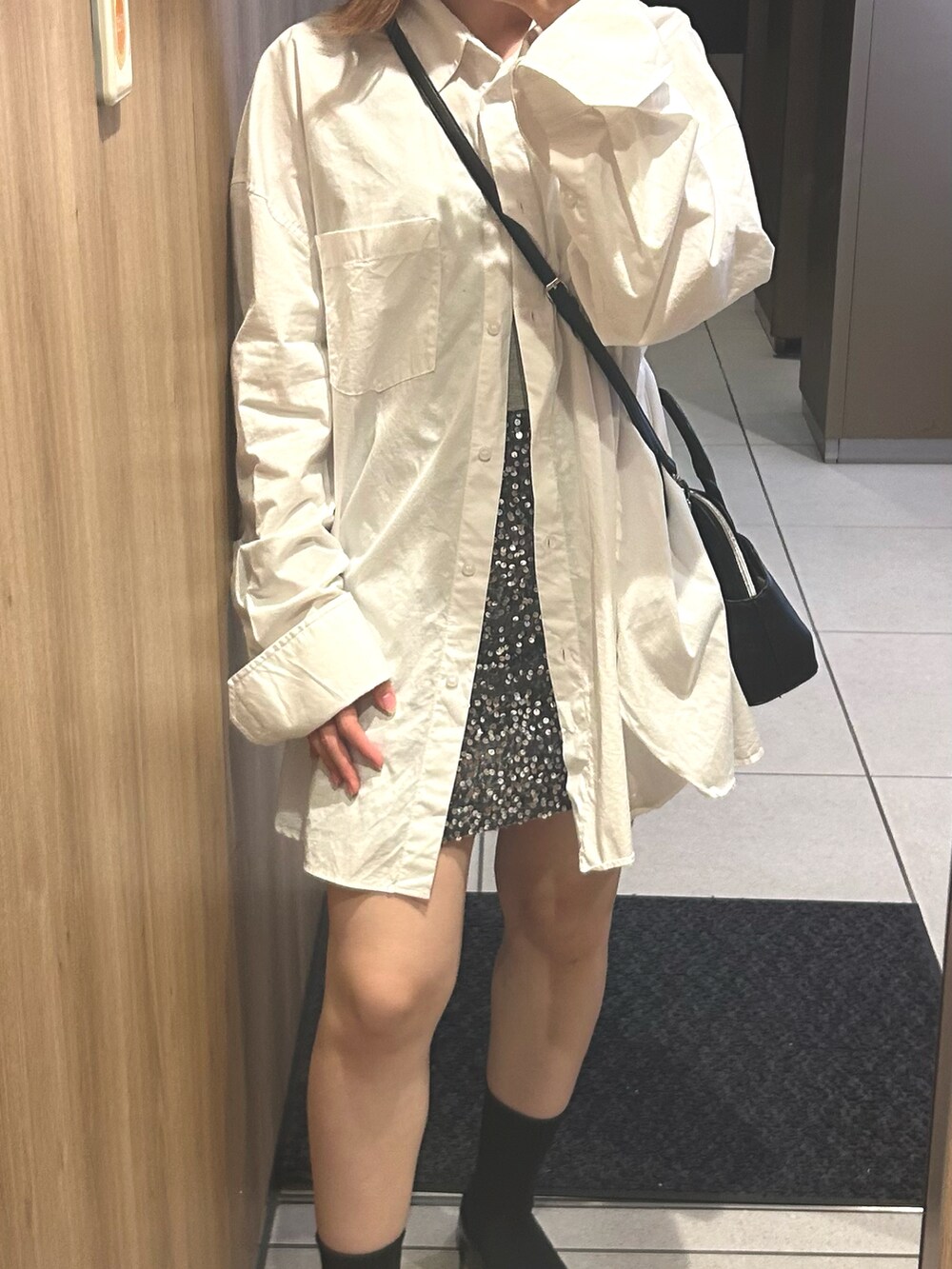 シルバー系のスカート、ブラック系のショルダーバッグ、ホワイト系のシャツ/ブラウスを着用したレディースの夏コーディネートの2枚目の写真