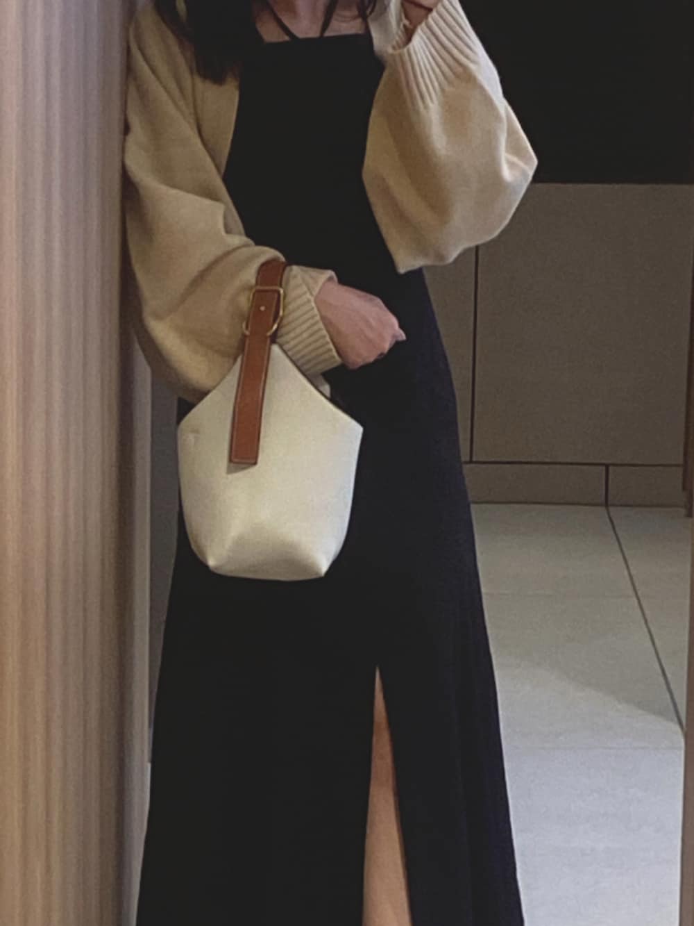 ホワイト系のハンドバッグ、シルバー系のスニーカー、ブラック系のワンピース/ドレスを着用したレディースの冬コーディネートの3枚目の写真