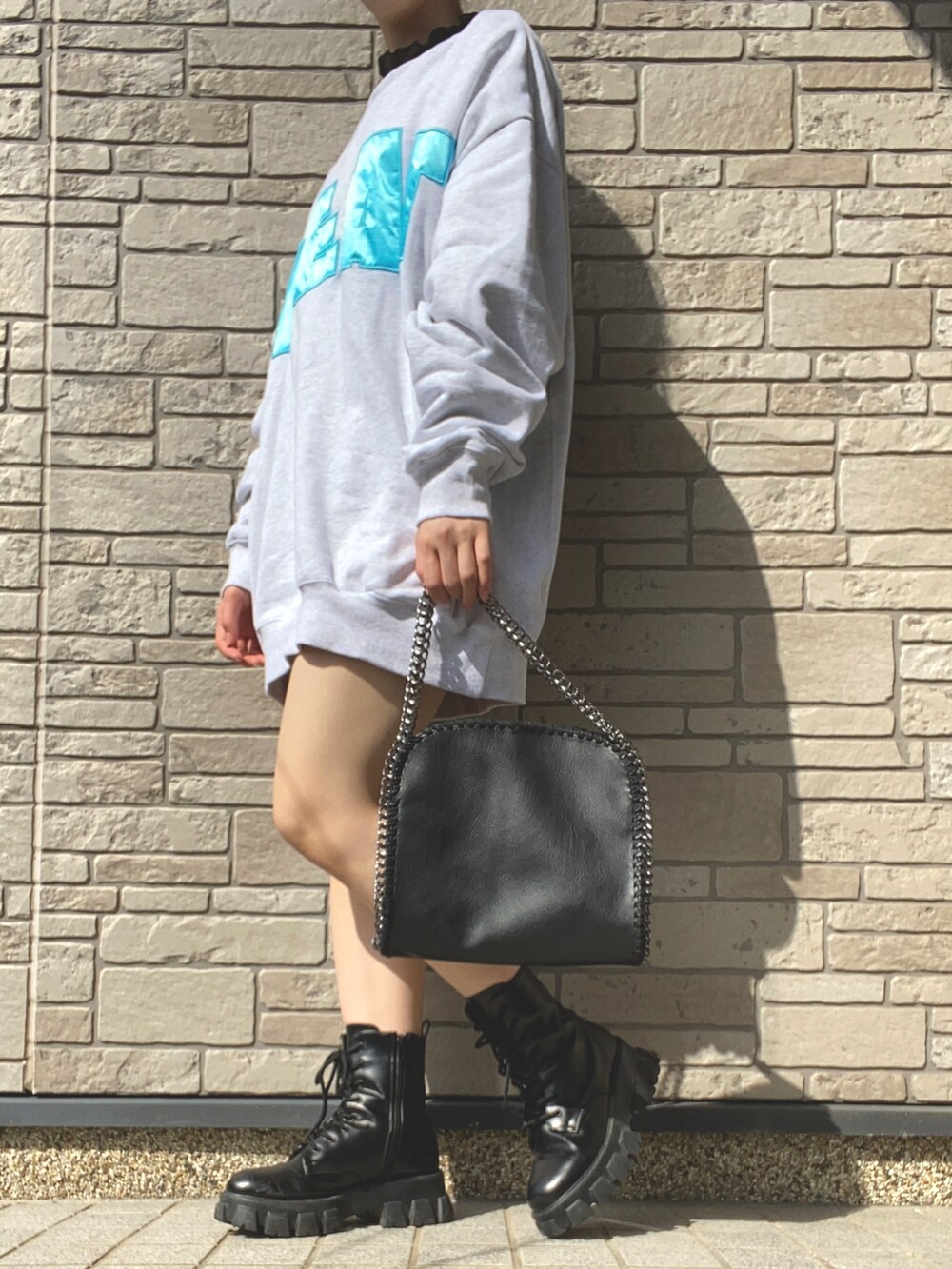 グレー系のスウェット、ブラック系のブーツ、ブラック系のハンドバッグを着用したレディースの春コーディネートの2枚目の写真