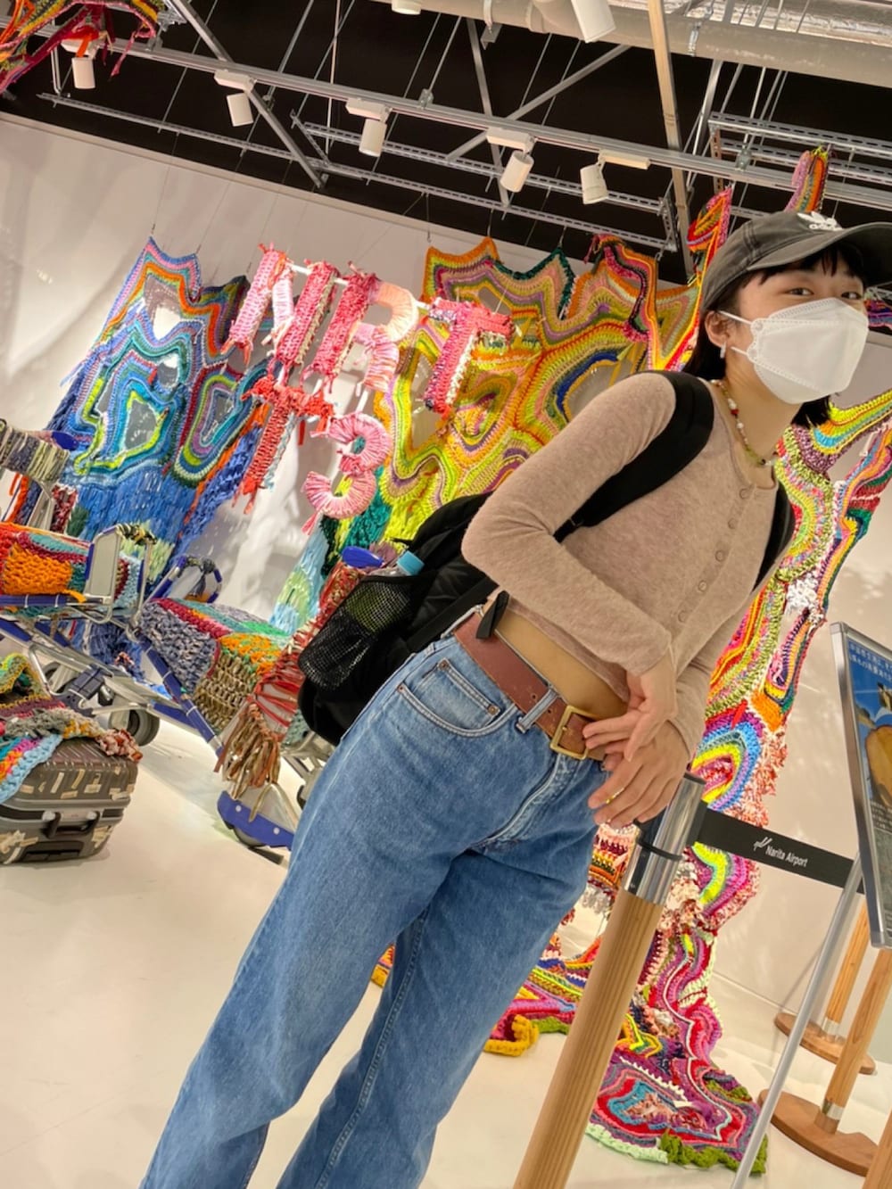 ブルー系のデニムパンツ、ベージュ系のカーディガン/ボレロ、ブラック系のキャップを着用したレディースの春コーディネートの3枚目の写真