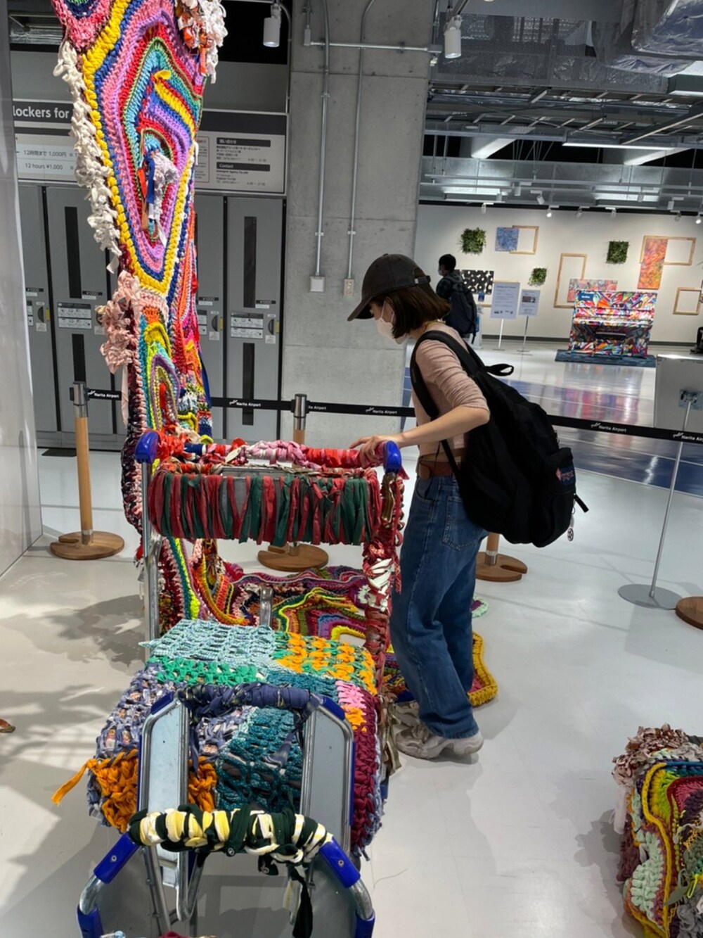 ブルー系のデニムパンツ、ベージュ系のカーディガン/ボレロ、ブラック系のキャップを着用したレディースの春コーディネートの2枚目の写真