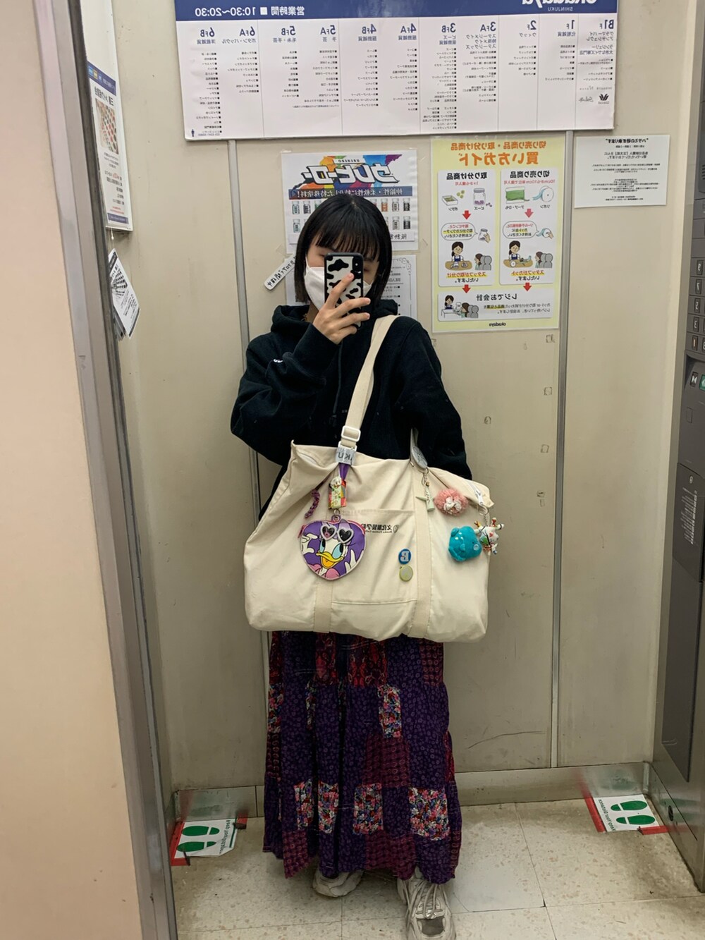 ブラック系のパーカー、パープル系のスカート、ホワイト系のトートバッグを着用したレディースの春コーディネートの2枚目の写真