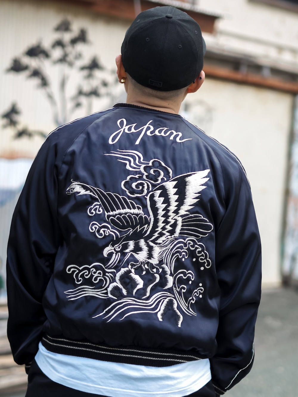 ブラック系のスカジャン、ブラック系のチノパンツ、ブラック系のスニーカーを着用したメンズの春コーディネートの3枚目の写真