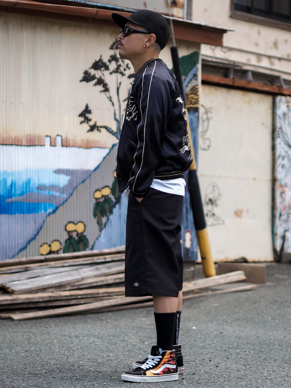 ブラック系のスカジャン、ブラック系のチノパンツ、ブラック系のスニーカーを着用したメンズの春コーディネートの2枚目の写真