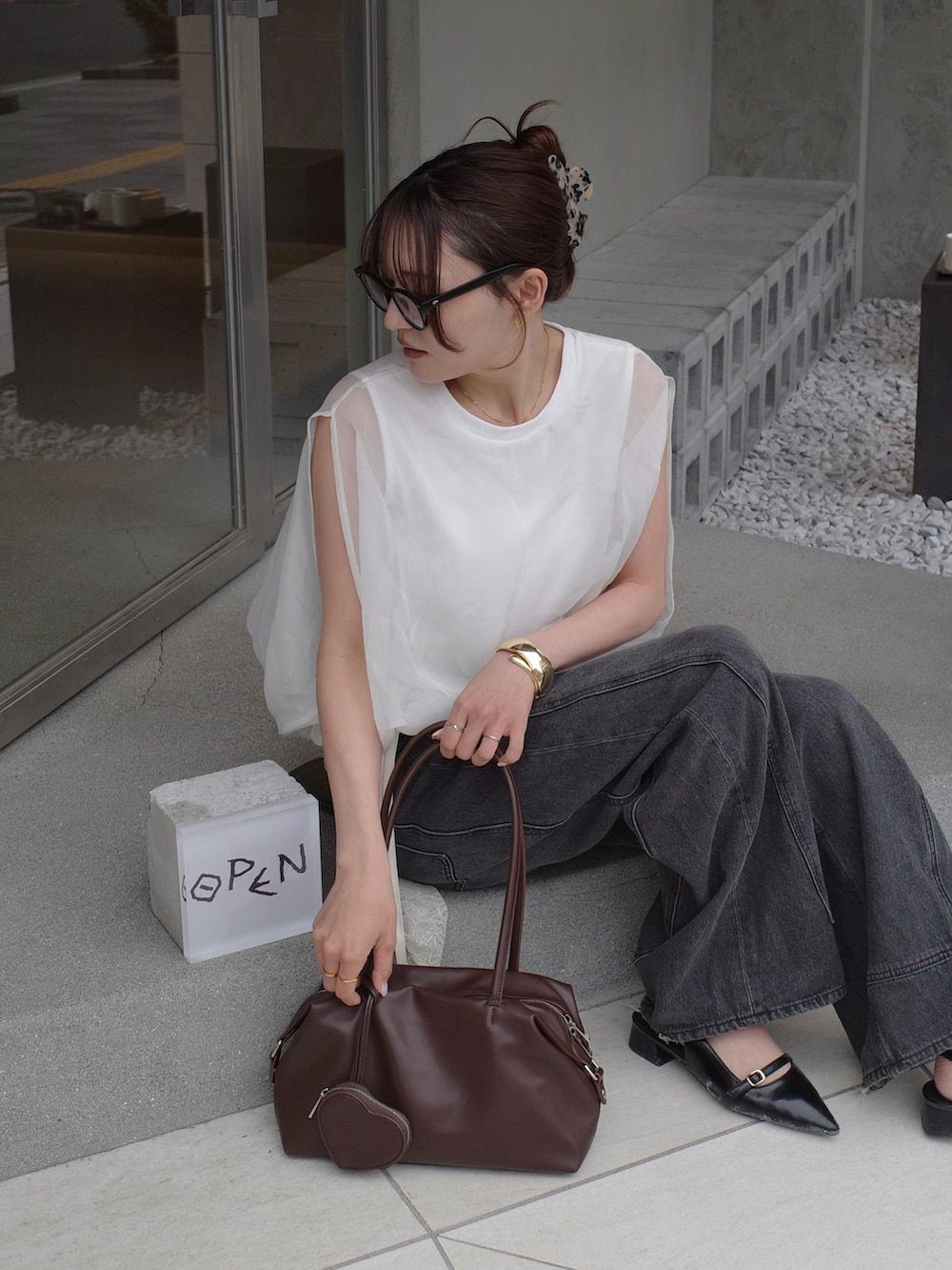 ホワイト系のシャツ/ブラウス、ベージュ系のボストンバッグ、ブラック系のデニムパンツを着用したレディースの夏コーディネートの2枚目の写真