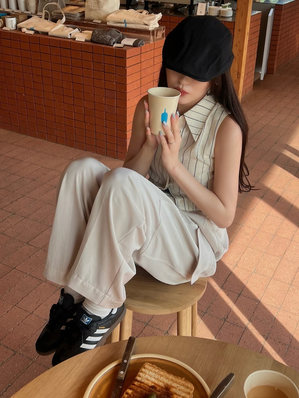 ホワイト系のカーゴパンツ、ブラック系のスニーカー、ブラック系のハンチング/ベレー帽を着用したレディースの春コーディネートの2枚目の写真