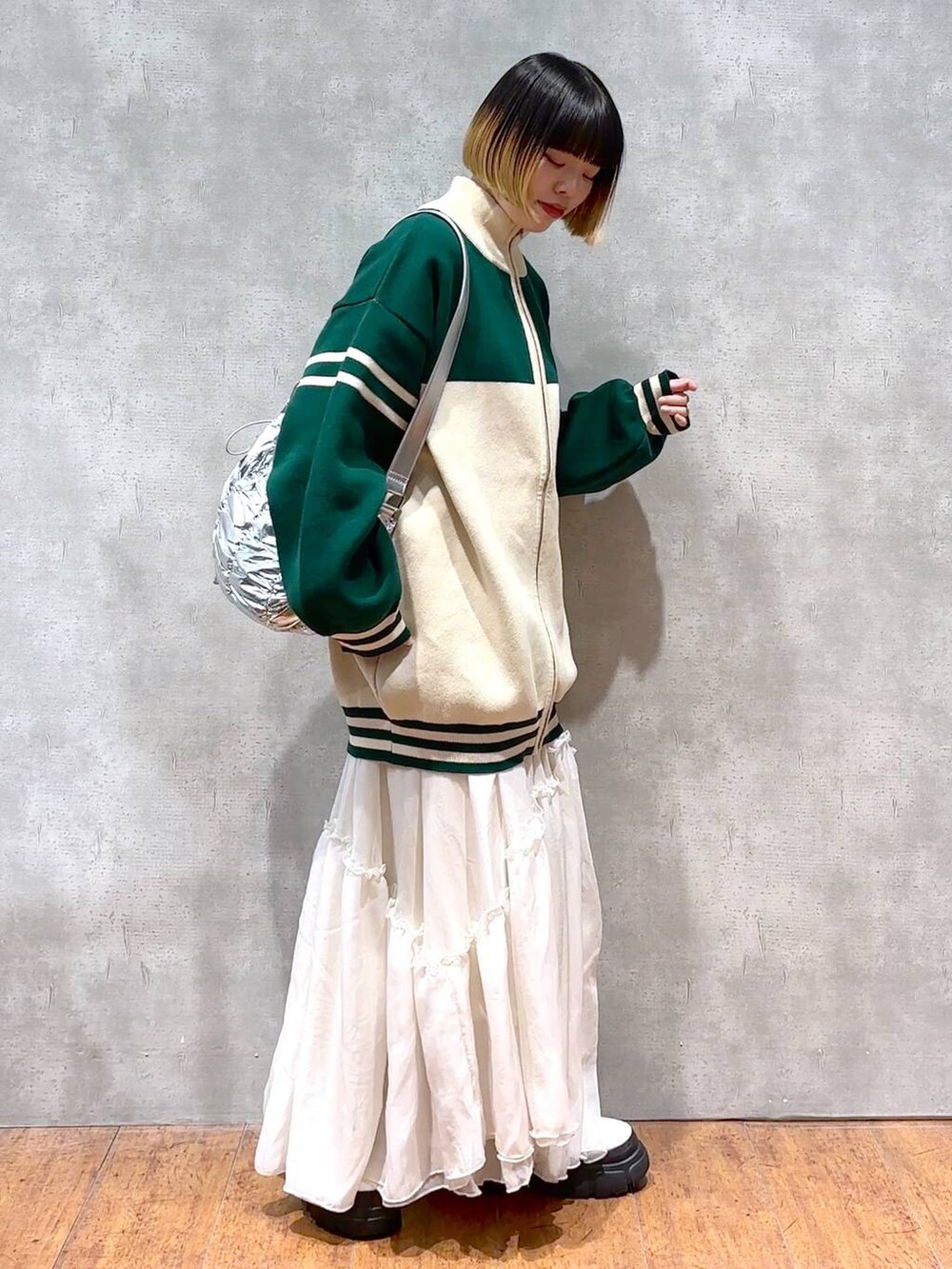 シルバー系のショルダーバッグ、グリーン系のニット/セーター、ホワイト系のブーツを着用したレディースの冬コーディネートの2枚目の写真