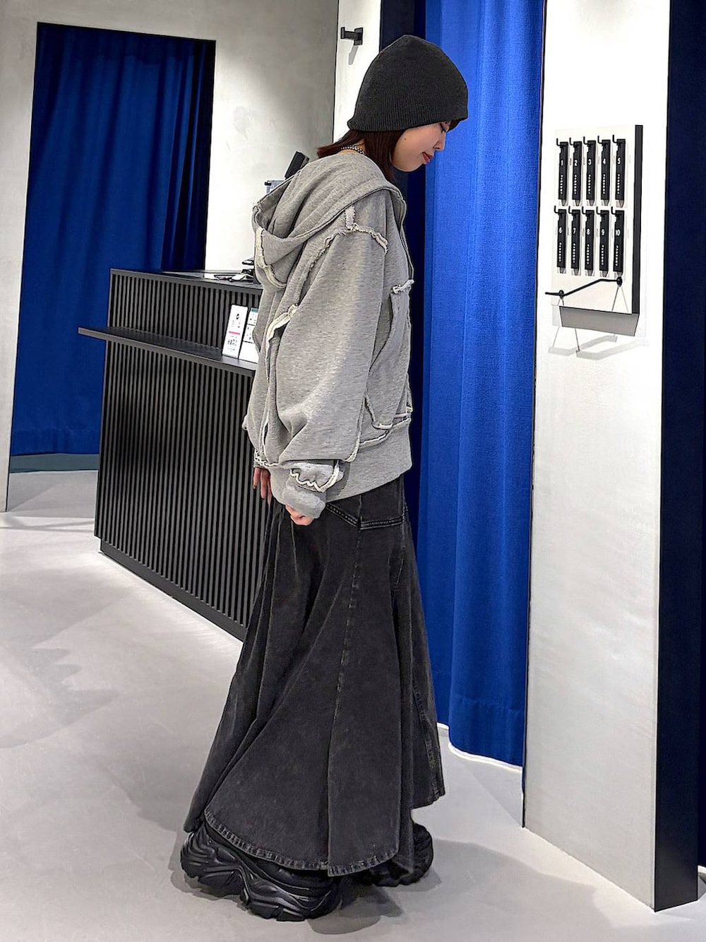 ブラック系のスニーカー、ブラック系のデニムスカート、グレー系のタンクトップを着用したレディースの春コーディネートの2枚目の写真