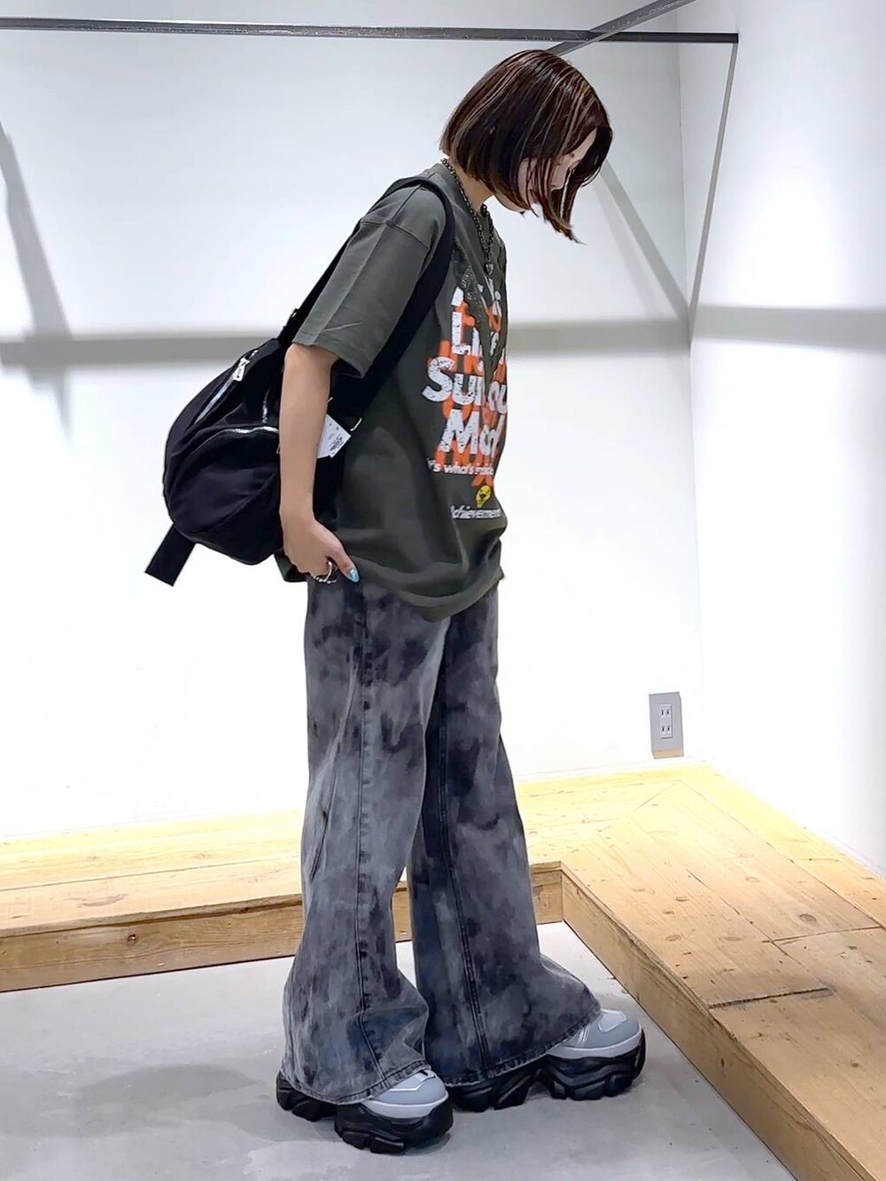 グレー系のスニーカー、ブラック系のデニムパンツ、ブラック系のショルダーバッグを着用したレディースの夏コーディネートの2枚目の写真