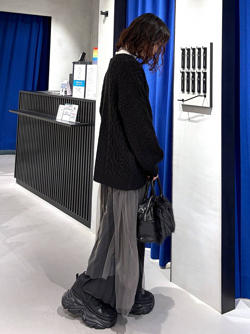 ブラック系のスニーカー、ブラック系のニット/セーター、ホワイト系のニット/セーターを着用したレディースの冬コーディネートの2枚目の写真